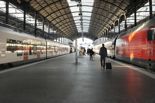 Ein Bahnhof mit zwei Gleisen mit einem weissem Zug und einem roten Zug