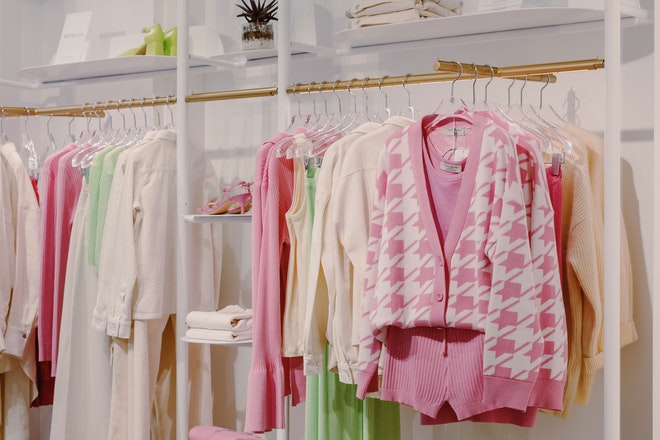 Kleidung in pink, weiss und grün hängt in einem Laden