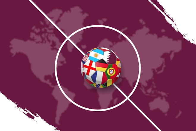 Ein Fussball mit verschiedenen Länderflaggen drauf verweilt auf dem Anstoss-Punkt eines Fussballfeldes. 