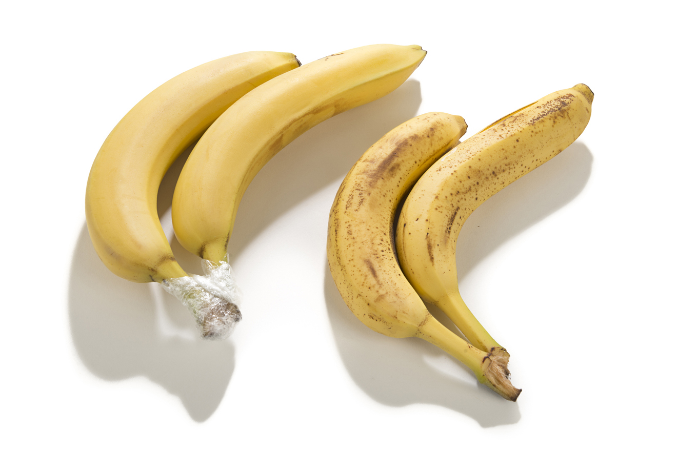zwei Paare Bananen, bei einem sind die Stengel in Plastikfolie eingepackt