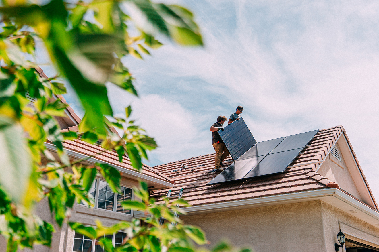 Zwei Männer installieren Photovoltaikanlagen auf einem Hausdach