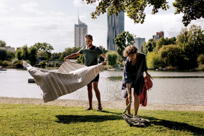 Zwei Personen legen ihre Decke ans Ufer der Donau in Wien