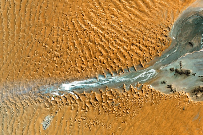 Blick von oben auf eine Wüste mit kleiner Wasserquelle