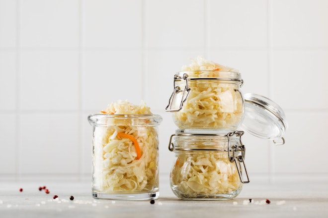Drei offene Gläser mit selbstgemachtem Sauerkraut stehen in einer hellen Küche