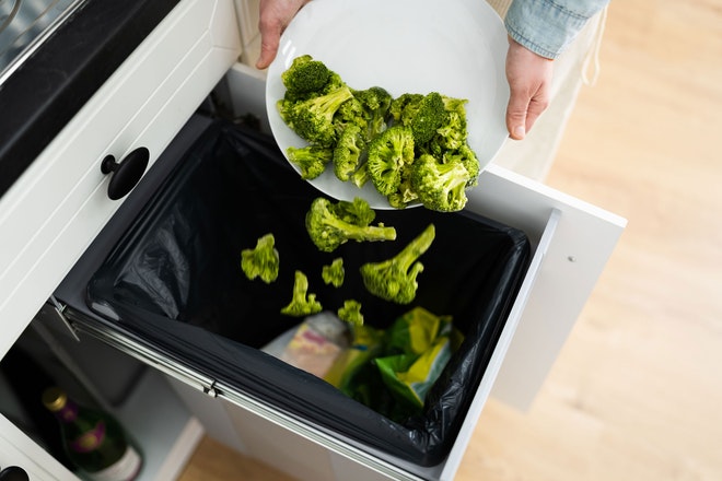 Person wirft gekochten Broccoli in den Abfall