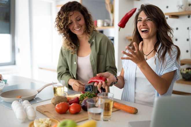 Zwei Frauen stehen in der Küche, haben Spass und kochen mit Gemüse