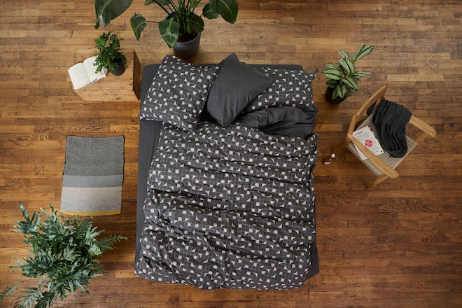 Ein Bett von oben mit grauer, gepunkteter Bettwäsche