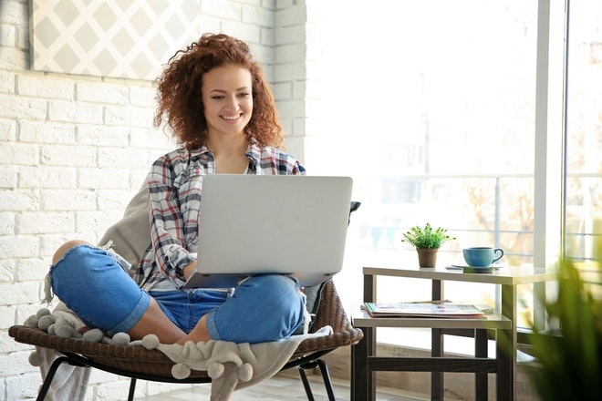 Junge Frau sitzt zuhause an einem Laptop