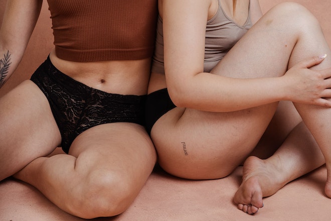 Zwei Frauen sitzen in Periodenunterhosen auf dem Boden
