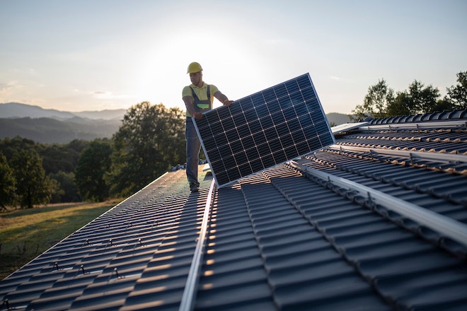 Handwerker installiert Sonnenkollektoren auf einem Hausdach