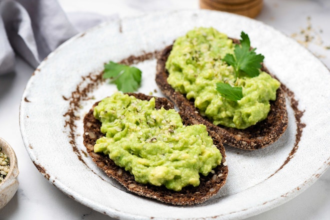 Two slices of brown bread with pea guacamole