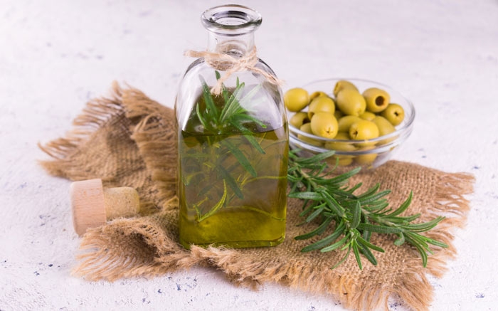 Wenn du Olivenöl verfeinern möchtest mit Kräutern wie Basilikum oder Rosmarien, kannst du die Kräuter in einer Flasche mit dem Öl aufbewahren. Nach und nach geben diese ihre charakteristische Würze an das Öl ab. Foto © Olivka888 / iStock / Getty Images Plus  