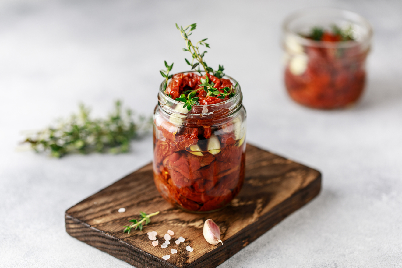 Getrocknete Tomaten im Glas mit Kräuterstengel darin