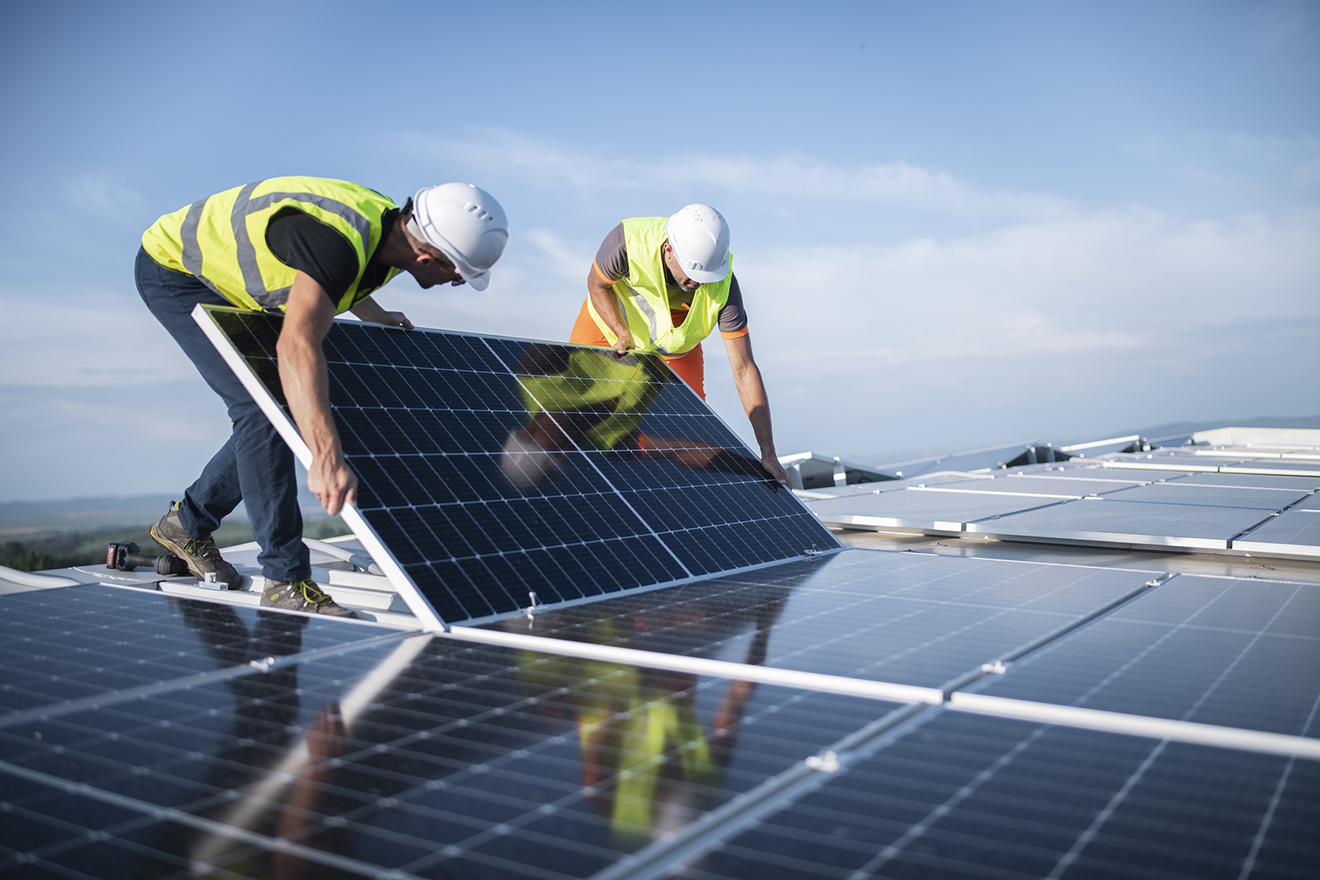 Team von zwei Ingenieuren, die Sonnenkollektoren auf dem Dach installieren.