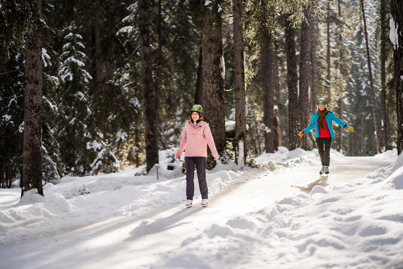 zwei junge Frauen fahren mit Schlittschuhen durch den Wald