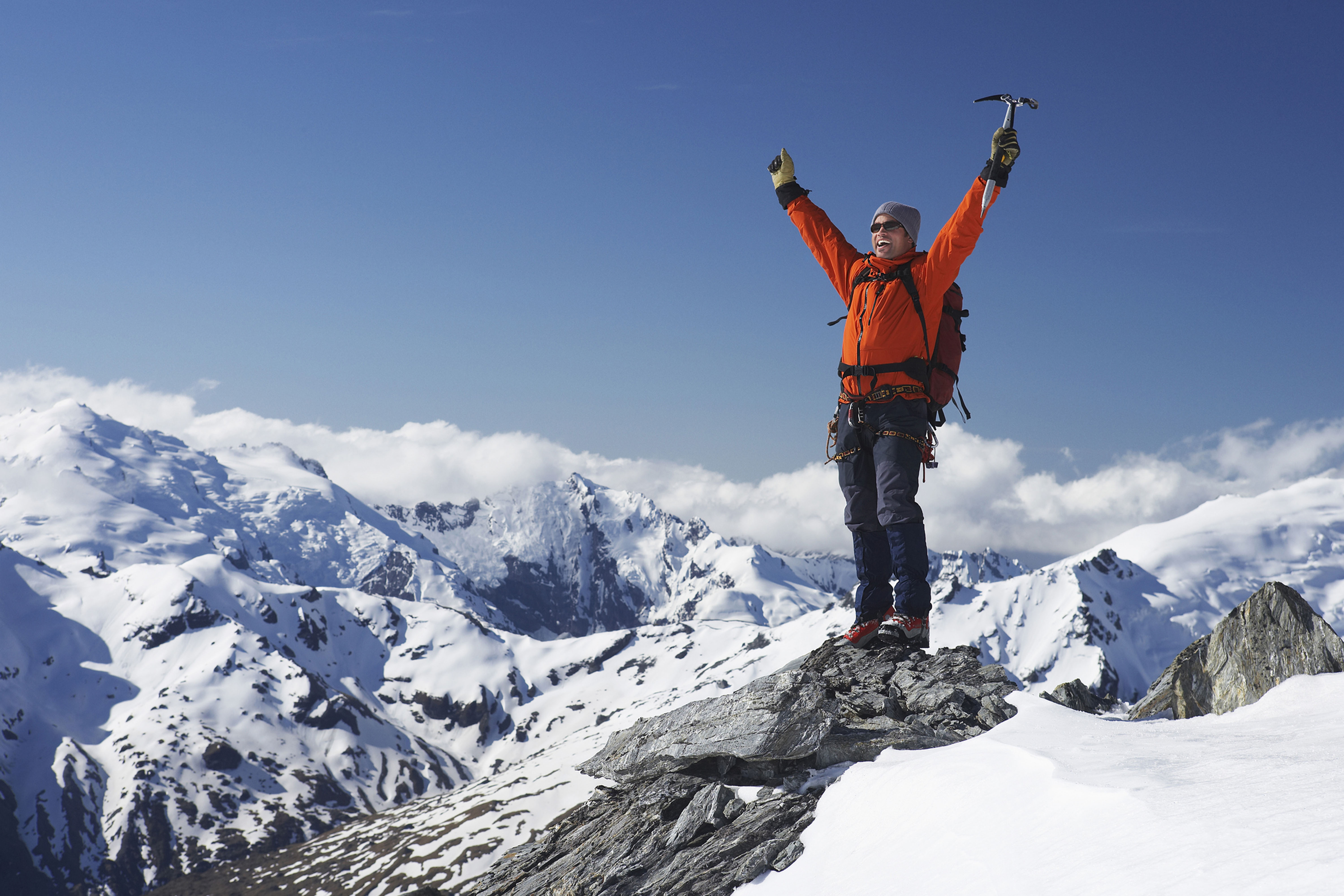 ein Mann steht auf der Bergspitze und streckt die Hände in die Luft