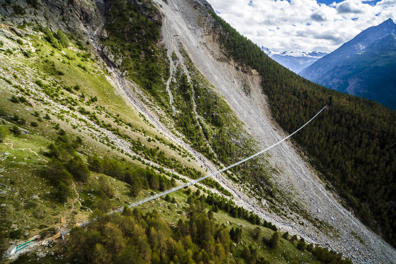 eine Hängebrücke führt über ein gigantisches Schotterfeld an einem Berghang