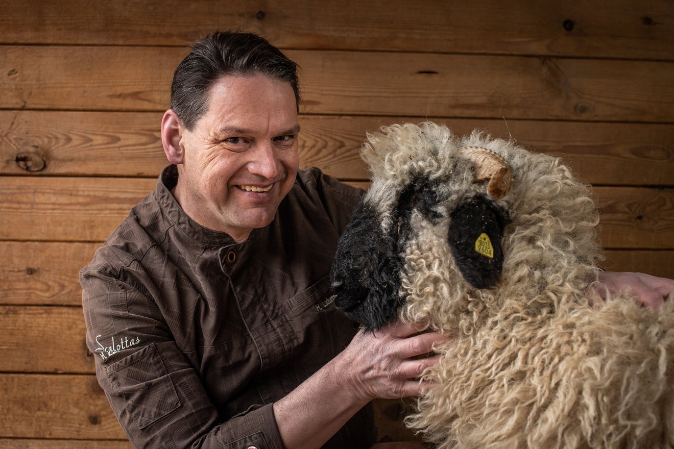 ein Mann beugt sich zu einem Schaf und lächelt